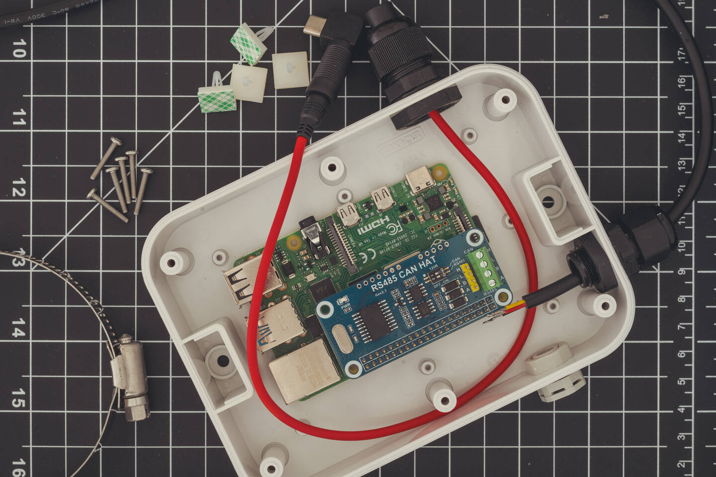 A Raspberry Pi 4 with an RS485 CAN HAT in a waterproof enclosure, surrounded by cables, screws and components.